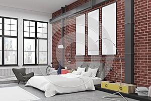 Corner of bedroom interior with brick walls and three narrow vertical posters on them.