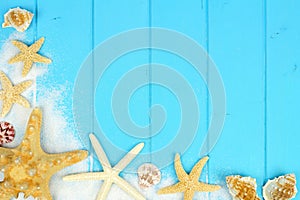 Corner border of sand, seashells and starfish on blue wood