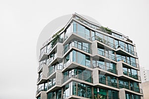 The corner of the building with many windows against the gray sky