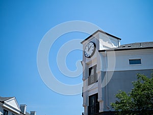 Corner of contemporary building with clock tower at 2 oclock in afternoon