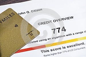 Corner of credit card on fake credit report with score on a desk