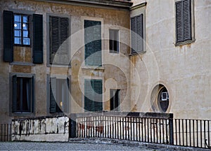 A corner formed by two facades of the Pitti Palace with two windows revealing lamps in the Boboli garden in Florence.