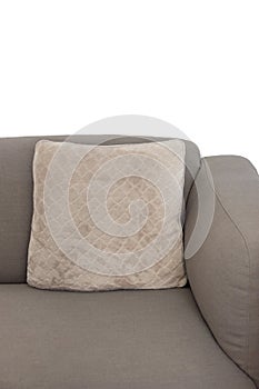Corner fragment of beige grey upholstered couch with velour decorative cushion on white wall background. Isolated
