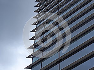 Corner of a futuristic building with steel geometric lines and blue glass windows reflecting a blue sky