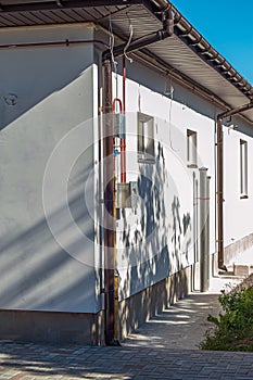 Corner of the house with new gray metal tile roof and rain gutter. Metallic Guttering System, Guttering and Drainage