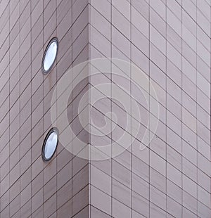 Corner of a large modern commercial building with grey rectangular cladding and round windows