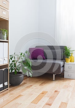 Corner of a living room with gray armchair and plants