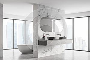 Corner of modern bathroom with double sink and white bathtub, large panoramic window, city view, minimalistic marble and concrete