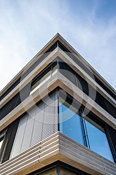 Corner of a modern concrete office building with external blinds and large windows