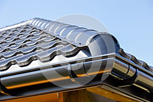 Corner of the new modern house with roof and gutter  under blue sky