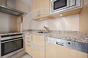 Corner of a newly installed modern kitchen with pink granite worktops, light