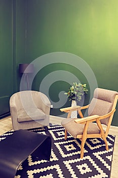 A corner part of the living room interior with an empty green wall for your design, poster, painting. An armchair, a