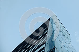 Corner of a skyscraper under a cloudy and cold sky seen from the bottom