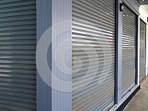 Corner of storefront, gray metal roller shutter door of shop in flea market is closed and locked