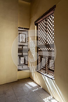 Corner of two Interleaved wooden ornate windows - Mashrabiya - in stone wall photo