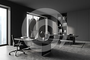 Corner view on dark grey office room interior with meeting board, desk with desktop computer, armchair, panoramic windows,