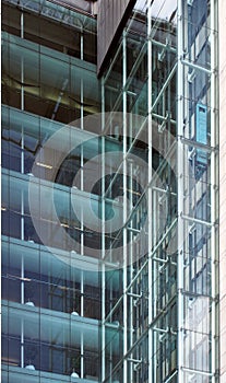 Corner view of elevators and stories in a tall modern glass corporate building with walls reflected in the windows