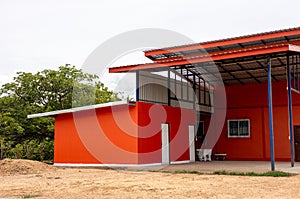 A corner view of the exterior of an orange building with a newly constructed