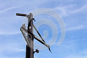 Corner view of rusted metal pole and outriggers against a blue sky