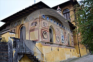 Corner view of two sides, with tree fronds, of the ancient Stibbert villa in Florence, both decorated, but definitely more beautif