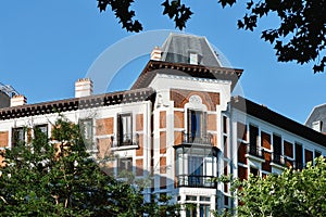 Corner of vintage old fashioned seen through vivid greenery in Chamartin district downtown Madrid, Spain. Spanish vintage