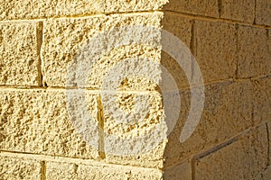 The corner of the wall with imitation brickwork light yellow. Light and shadow. Background