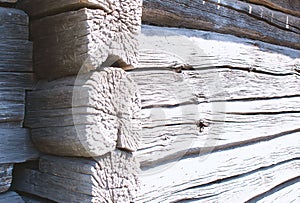 A corner and wall of an old, gray, wooden barn close-up. Corner of a wooden peasant house..