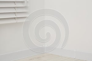 Corner of white wall with baseboard indoors