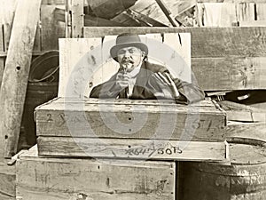 Cornered man behind wooden crates pointing gun