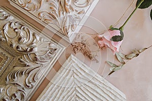 Corners of decorative wooden white frames and rose on beige canvas backdrop. Framer workshop concept.