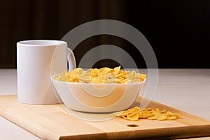 Cornflake cereals in a bowl with milk on light background, quick breakfast