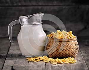 Cornflakes in basket and glass of milk on wooden table