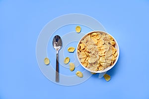 Cornflakes in bowl on blue background spoon for cereal healthy food