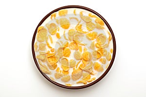 Cornflakes in a bowl with milk on a white background, top view