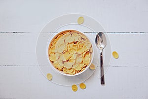 Cornflakes breakfast in bowl and spoon on wooden background - cereal healthy food