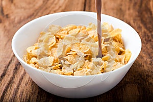 Cornflakes cereal pouring chocolate milk on wood table