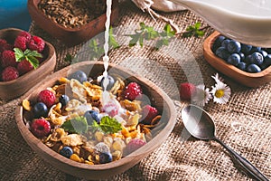 Cornflakes and other cereals with fresh fruits of raspberries, blueberries and milk