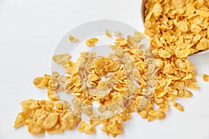 Placer of cornflakes with a metal bowl on a painted white wooden background. Cornflakes scattered on a wooden table. photo