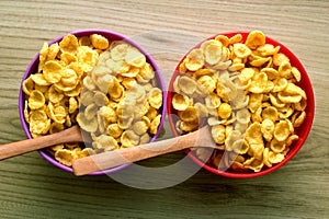 Cornflakes in small bowls with wooden spoons