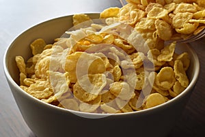 Cornflakes spilling out of a plastic bag in a white bowl.