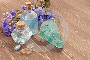 Cornflower flower blue water in glass bottles, natural stones and flowers on brown wooden background