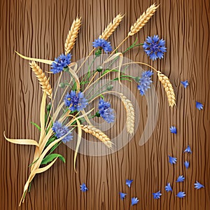 Cornflowers and wheat ears on wood background
