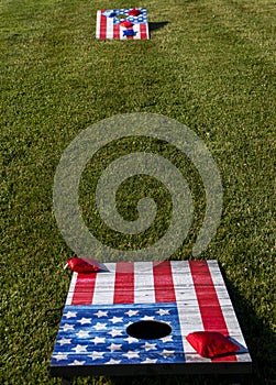 Cornhole boards painted as American flags on a thick green lawn