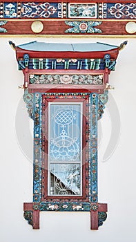 Cornice, old wooden window with platbands, with traditional colorful decor of dugan,Buddhist temple