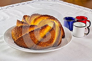 Cornmeal cake. Typical Brazilian cornmeal cake on a white porcelain plate with enameled colored agate coffee cups on the side