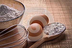 Corolla eggs flour in spoon bowl on wooden board