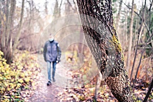 Corona depression, anxiety, loneliness and social distancing concept. Lonely sad man walking in forest alone during coronavirus.