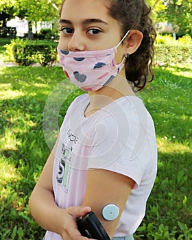 Corona virus  and diabetes. Girl with the mask on face checks glucose level in blood photo