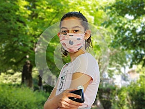 Corona virus  and diabetes. Girl with the mask on face is reading glucose level from the white sensor on left arm. photo