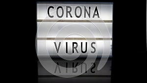 Corona virus letters on a light box on reflective surface